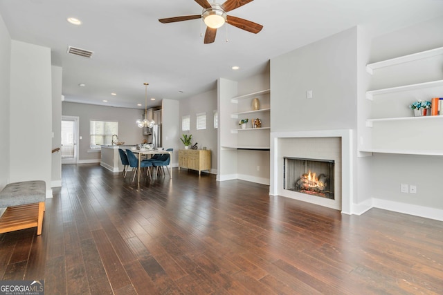 living room with ceiling fan with notable chandelier and dark hardwood / wood-style flooring