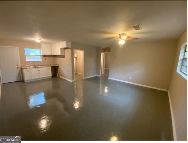 unfurnished living room featuring ceiling fan and sink