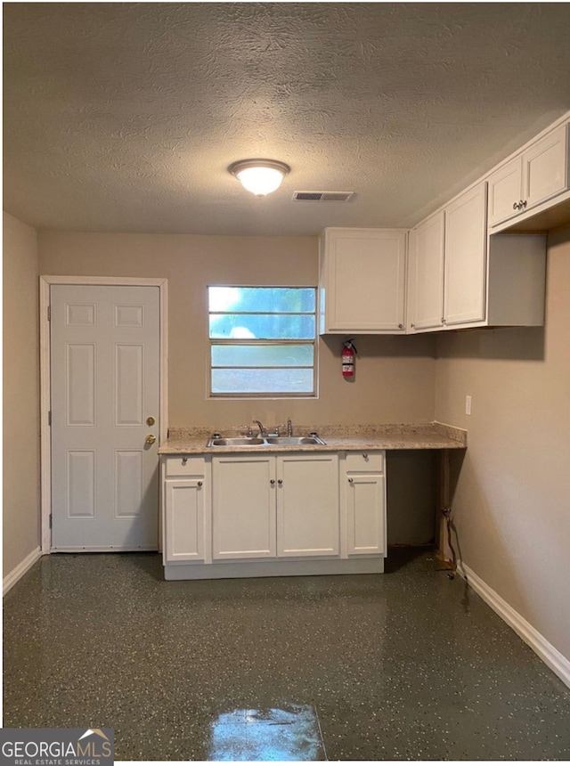 kitchen featuring a textured ceiling, sink, and white cabinets