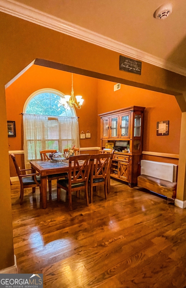 dining room featuring an inviting chandelier, crown molding, and dark hardwood / wood-style flooring