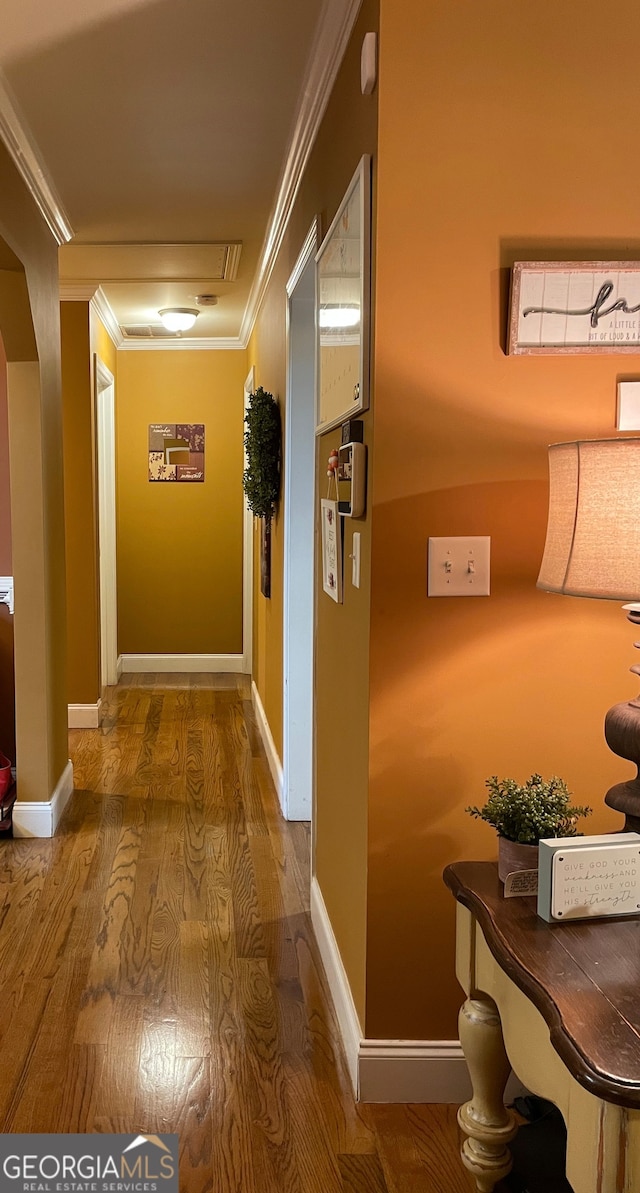 corridor with ornamental molding and hardwood / wood-style flooring