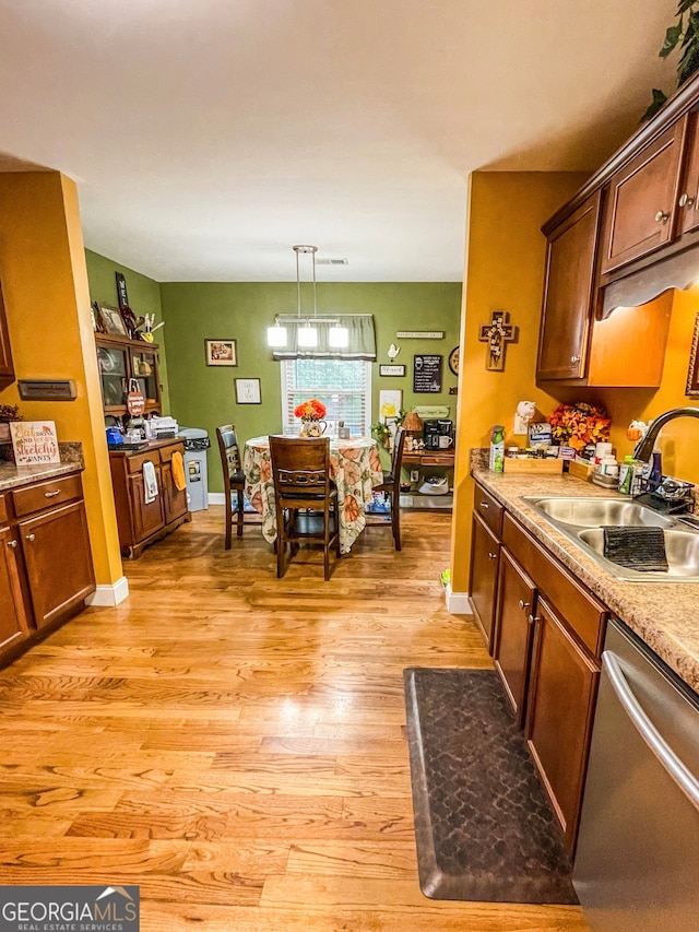 kitchen with sink, stainless steel dishwasher, decorative light fixtures, a chandelier, and light wood-type flooring