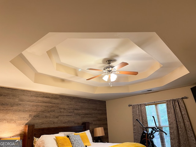 details featuring wooden walls, ceiling fan, and a raised ceiling