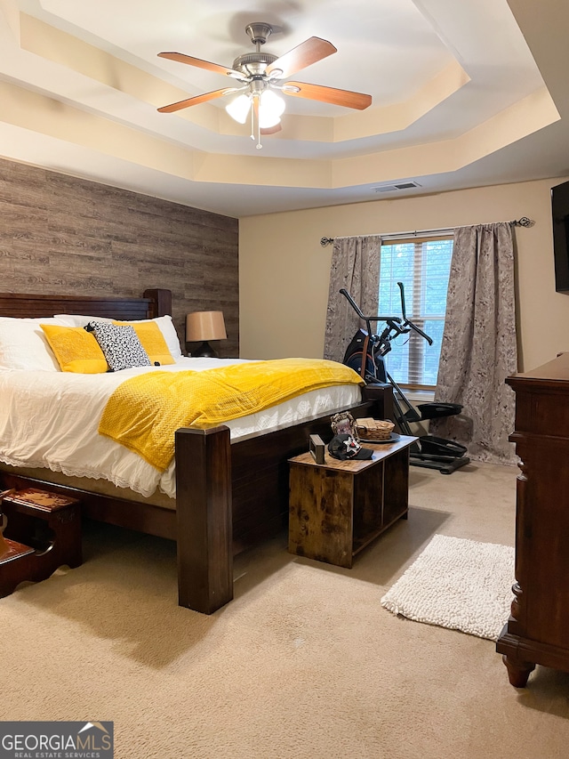 bedroom featuring ceiling fan, light colored carpet, and a tray ceiling