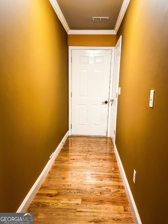 doorway with crown molding and light hardwood / wood-style floors