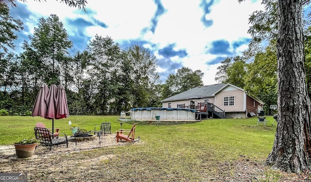 view of yard with a pool side deck and an outdoor fire pit