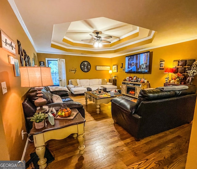 living room featuring ceiling fan, hardwood / wood-style flooring, a fireplace, and crown molding