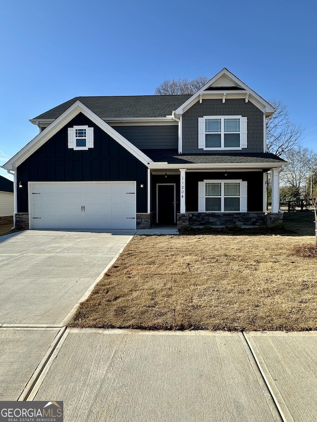 view of front of house featuring stone siding, a garage, board and batten siding, and driveway