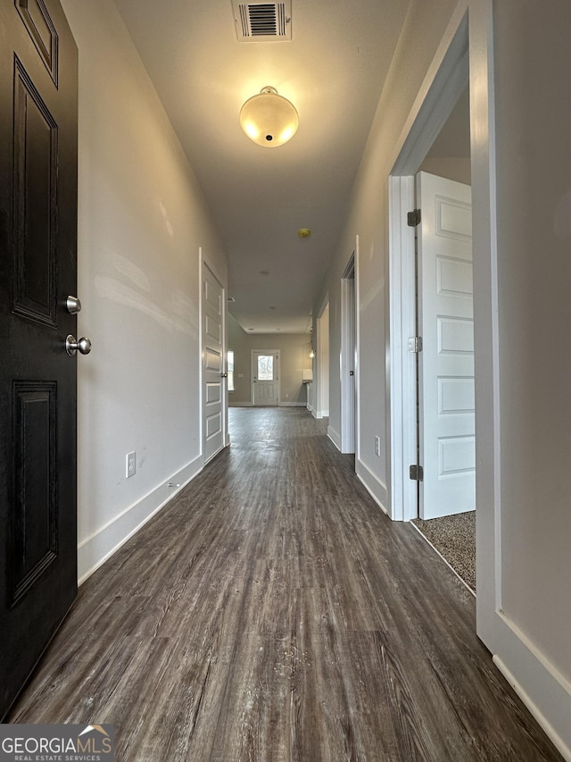 hallway featuring baseboards, visible vents, and dark wood finished floors