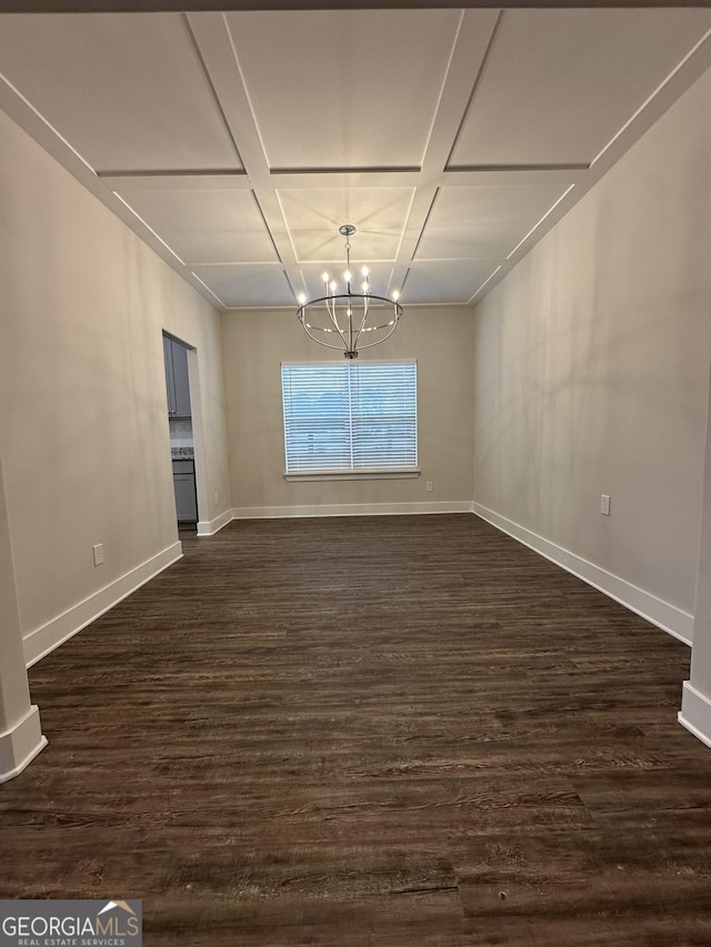 unfurnished dining area featuring dark wood-type flooring, coffered ceiling, a notable chandelier, and baseboards