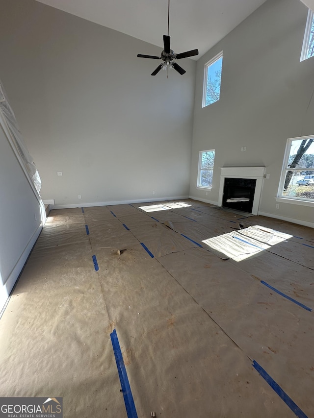 unfurnished living room with a towering ceiling, plenty of natural light, and ceiling fan