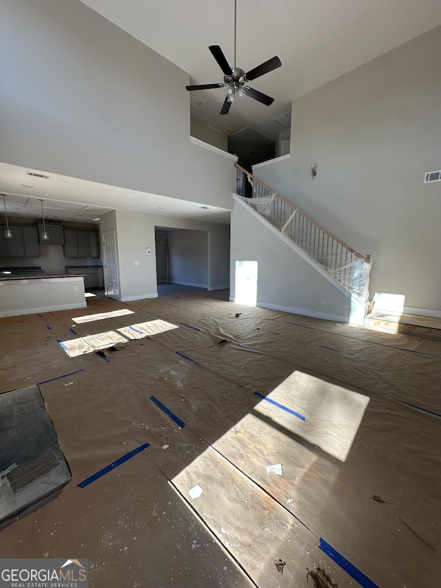 unfurnished living room featuring ceiling fan and a towering ceiling