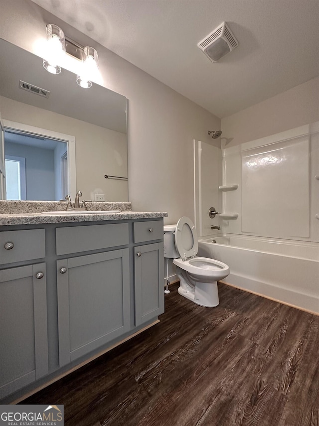 full bathroom featuring vanity, hardwood / wood-style floors, shower / bathtub combination, and toilet