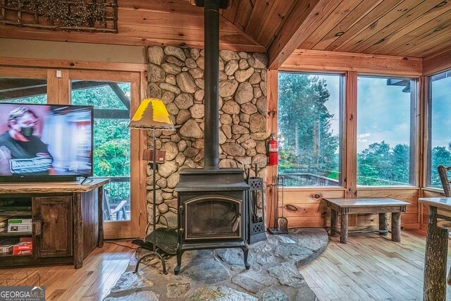 interior space featuring a wood stove, lofted ceiling, hardwood / wood-style flooring, and plenty of natural light