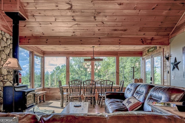 living area with a wood stove, wood ceiling, wood finished floors, and lofted ceiling