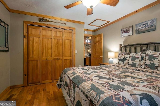 bedroom with hardwood / wood-style flooring, ornamental molding, a closet, a ceiling fan, and baseboards