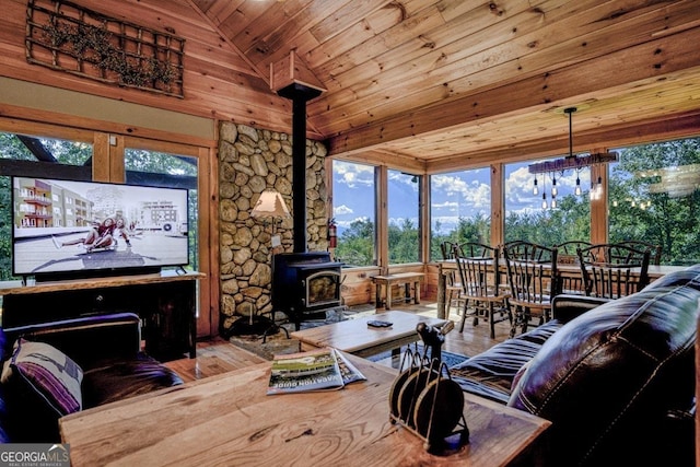 living area featuring a wood stove, wood ceiling, vaulted ceiling, and wood finished floors