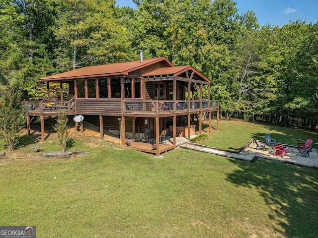 rear view of house featuring a fire pit, a patio, a deck, a yard, and a wooded view