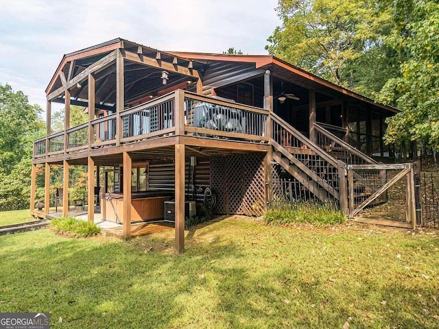 rear view of property featuring a hot tub, a deck, a yard, stairs, and central AC