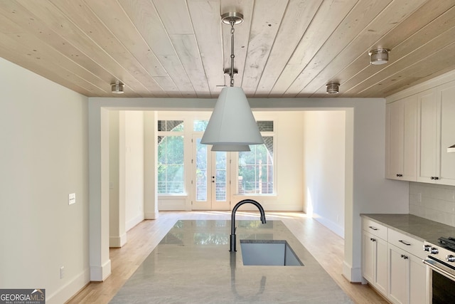 kitchen with sink, tasteful backsplash, decorative light fixtures, wood ceiling, and light wood-type flooring