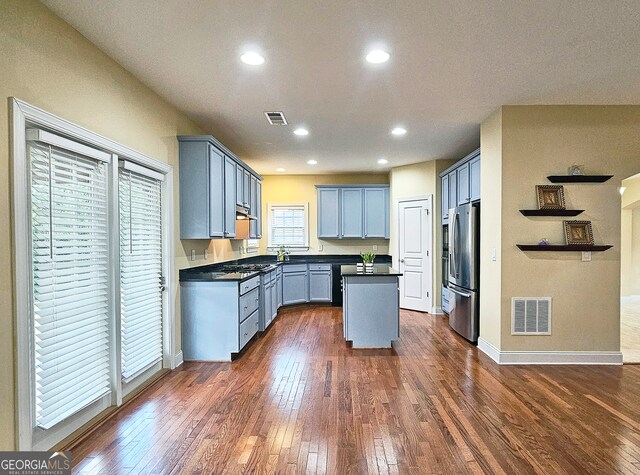 kitchen featuring blue cabinetry, appliances with stainless steel finishes, dark hardwood / wood-style flooring, and a kitchen island