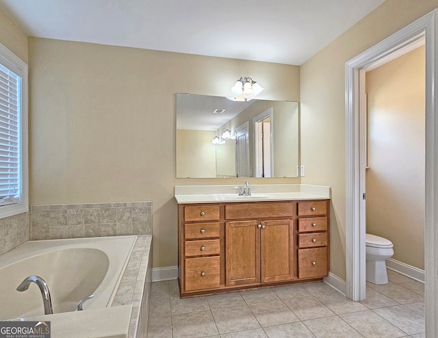 bathroom with tiled tub, vanity, toilet, and tile patterned floors