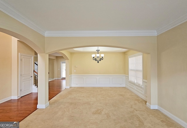 empty room featuring crown molding, carpet flooring, and an inviting chandelier