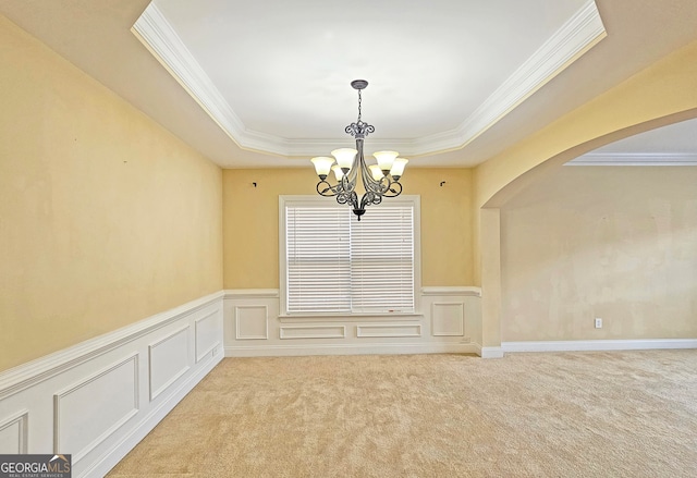 spare room featuring a raised ceiling, crown molding, light carpet, and a notable chandelier