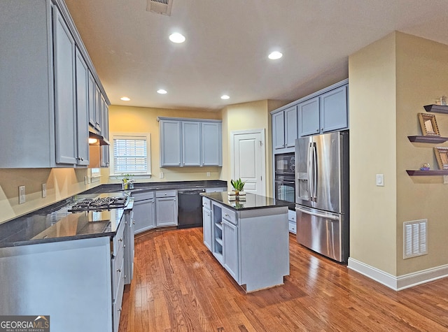 kitchen featuring black appliances, a kitchen island, and wood-type flooring