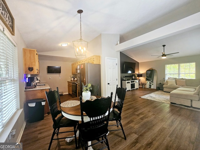 dining room featuring ceiling fan with notable chandelier, vaulted ceiling, and dark hardwood / wood-style flooring