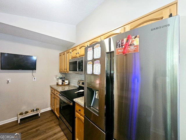 kitchen with appliances with stainless steel finishes, decorative backsplash, vaulted ceiling, light stone counters, and dark hardwood / wood-style flooring