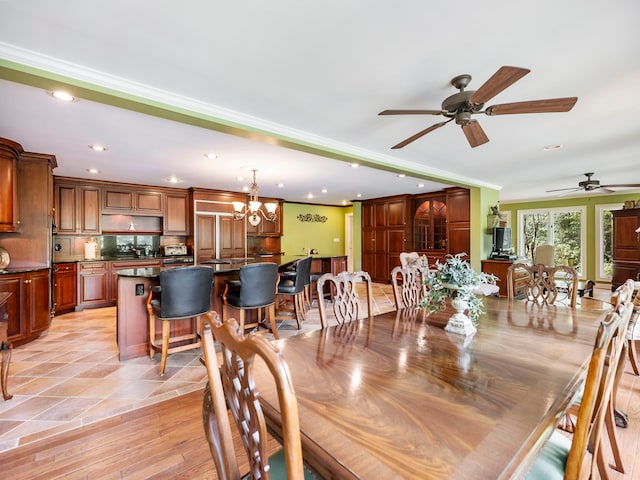 dining area with ceiling fan with notable chandelier, crown molding, and light hardwood / wood-style flooring