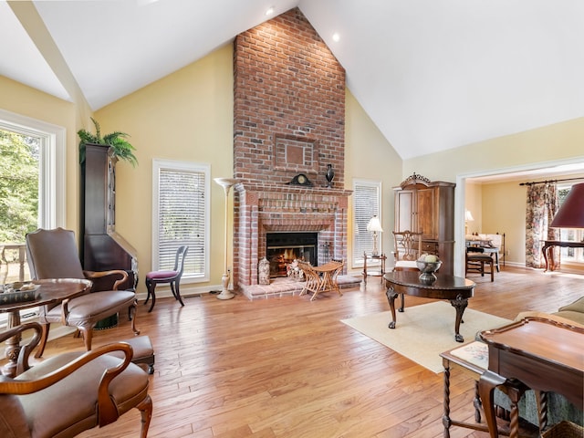 living room featuring a fireplace, light wood-type flooring, and high vaulted ceiling