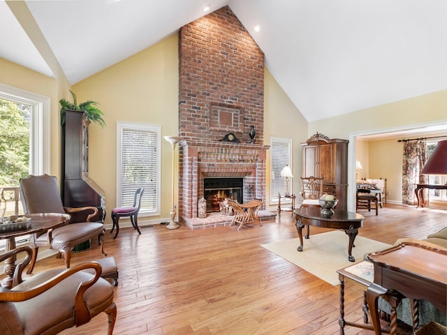 4394 Holly Springs Rd, Pendergrass, GA 30567 - living area featuring baseboards, high vaulted ceiling, light wood-type flooring, and a brick fireplace