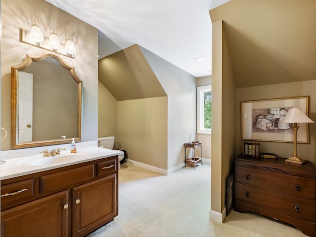 bathroom featuring vanity, toilet, and vaulted ceiling