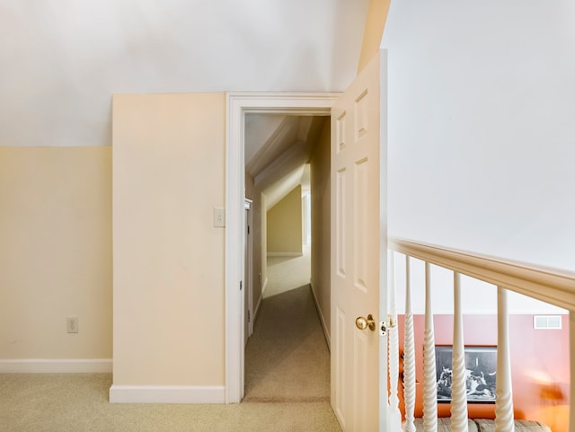 hall with vaulted ceiling and light colored carpet