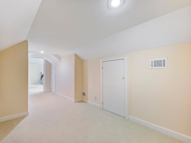 additional living space featuring light carpet and vaulted ceiling