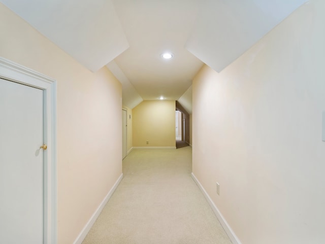 hallway featuring lofted ceiling and light colored carpet