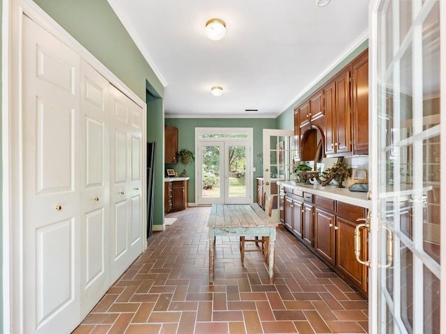 4394 Holly Springs Rd, Pendergrass, GA 30567 - kitchen with crown molding, light countertops, french doors, brick floor, and brown cabinetry