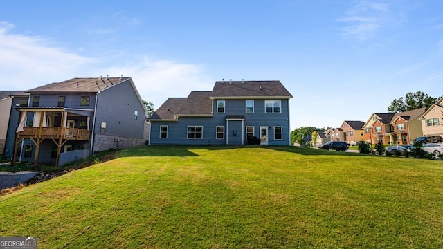 rear view of property with a balcony and a yard