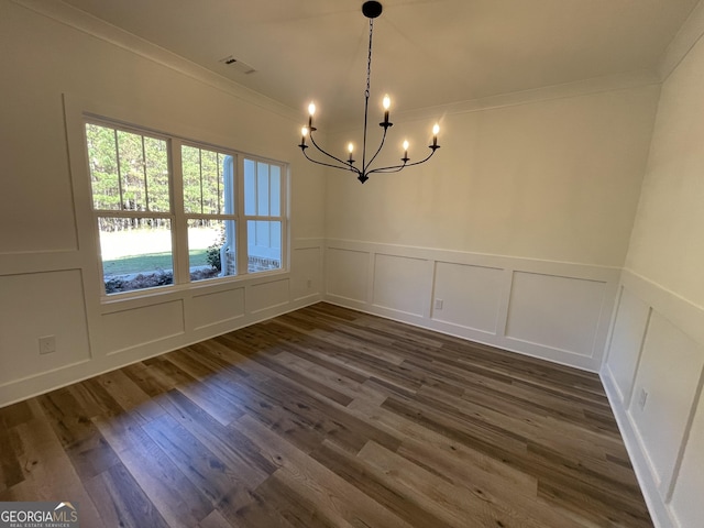 unfurnished dining area featuring an inviting chandelier, dark hardwood / wood-style floors, and crown molding