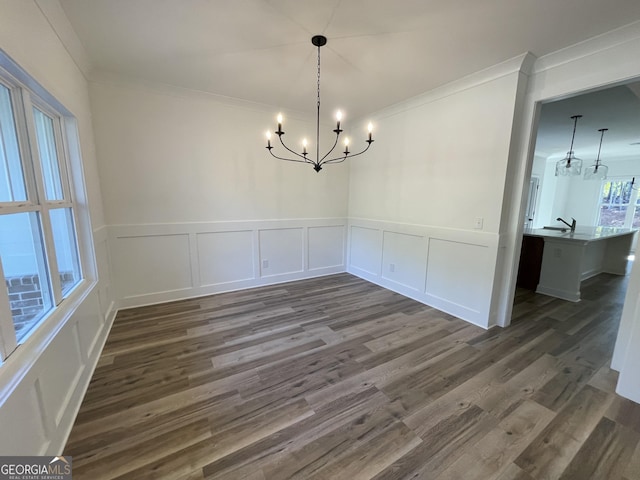 unfurnished dining area with crown molding, dark wood-type flooring, and a chandelier