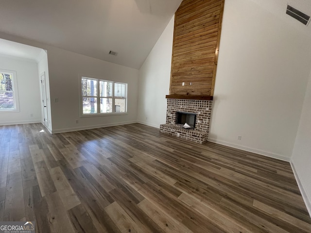 unfurnished living room featuring a brick fireplace, plenty of natural light, high vaulted ceiling, and dark hardwood / wood-style floors