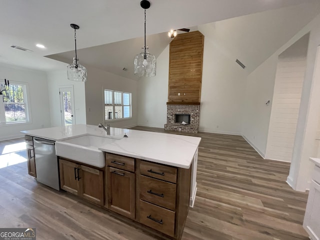 kitchen featuring hanging light fixtures, dishwasher, sink, and an island with sink