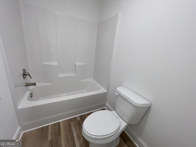 bathroom with hardwood / wood-style floors, tub / shower combination, and toilet