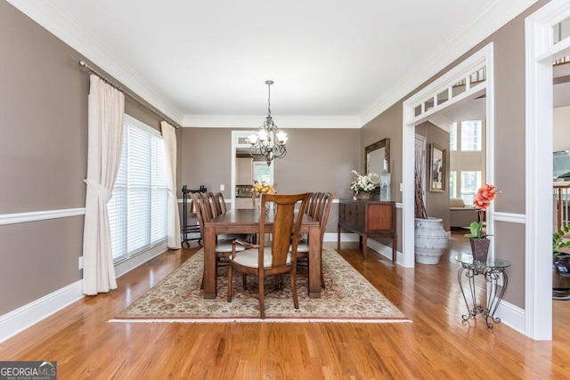 dining space with hardwood / wood-style flooring, an inviting chandelier, and crown molding