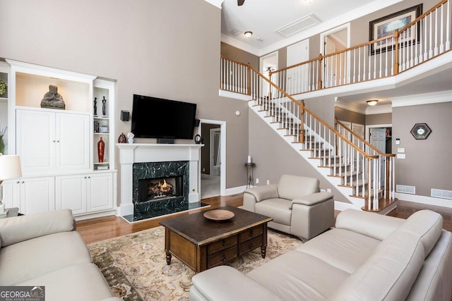 living room with built in shelves, light hardwood / wood-style floors, a premium fireplace, and a high ceiling