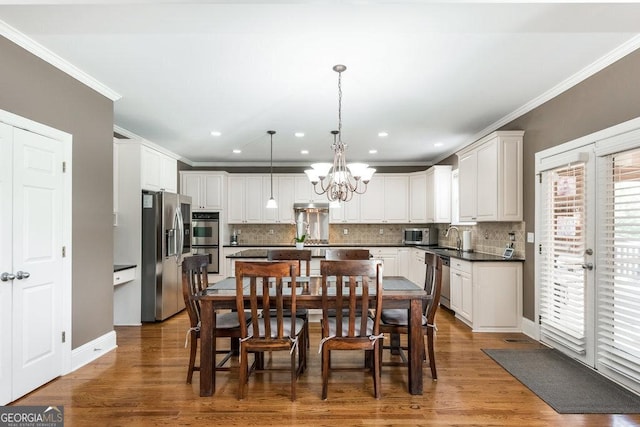 dining room featuring hardwood / wood-style floors, sink, crown molding, and an inviting chandelier