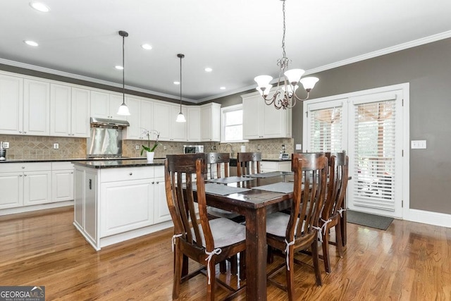 dining space with a chandelier, crown molding, and light hardwood / wood-style floors