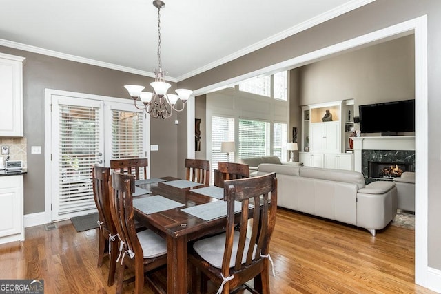 dining space with a fireplace, plenty of natural light, light hardwood / wood-style floors, and a notable chandelier